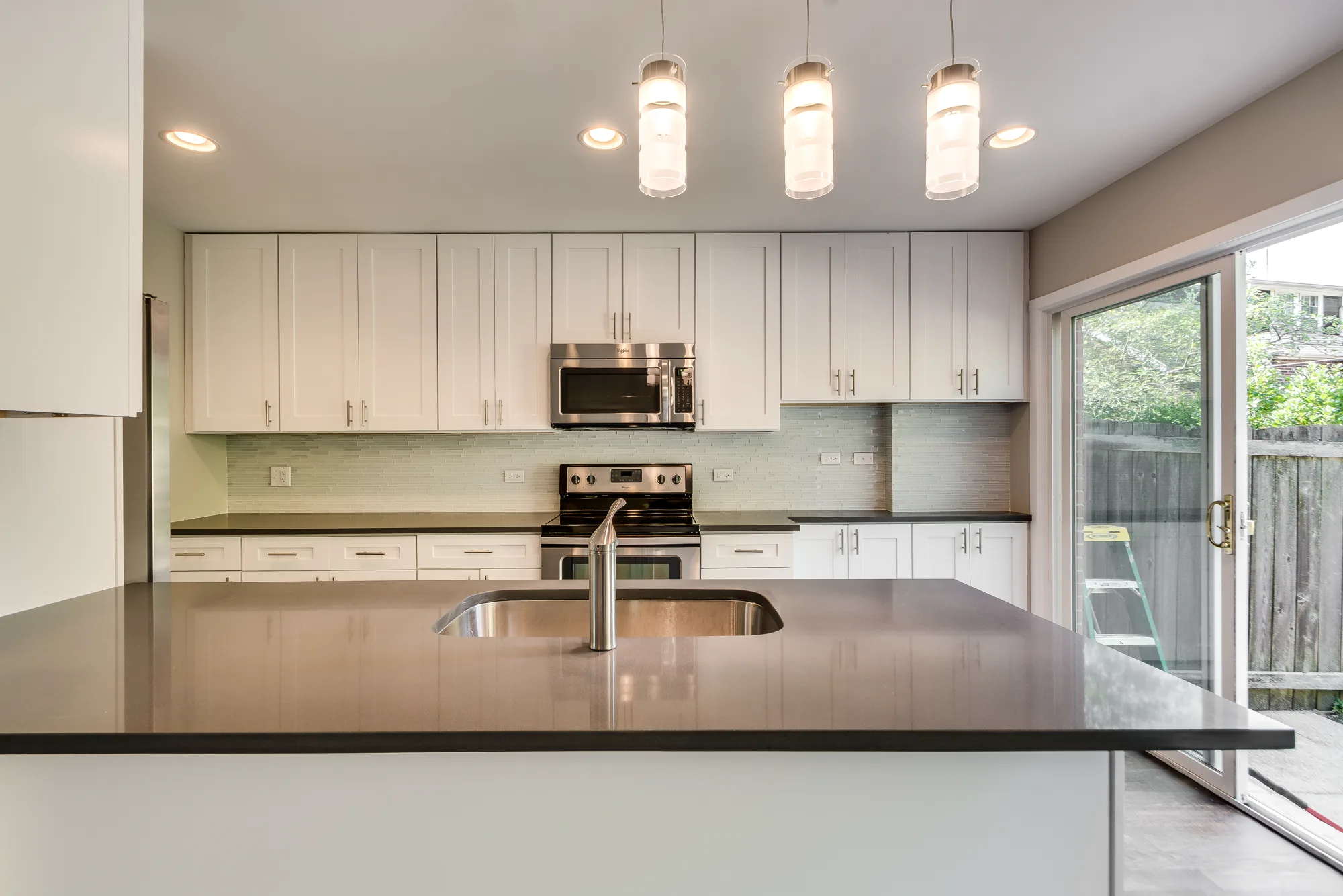 Rehabbed kitchen with glass backsplash and shaker cabinetry