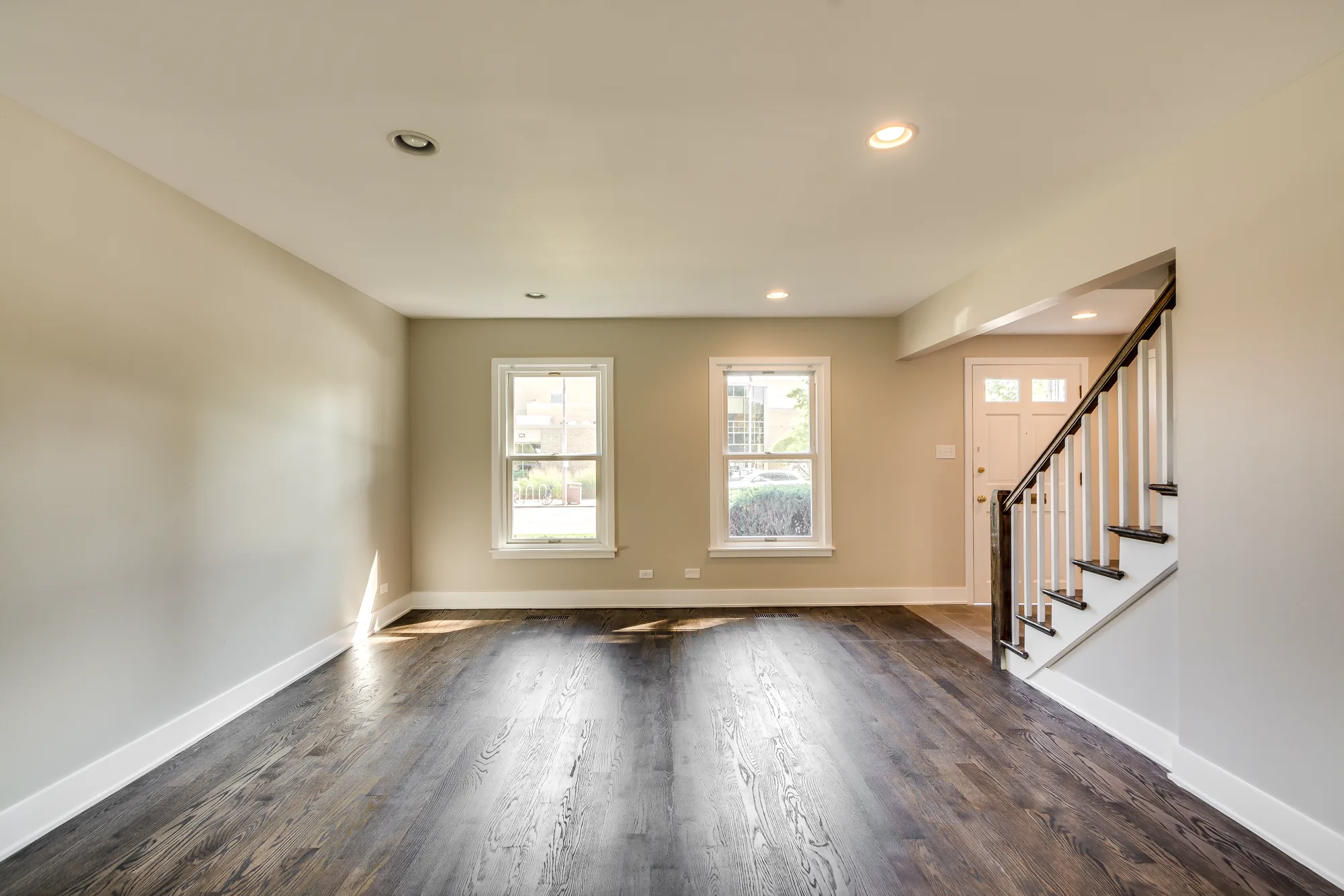 Living room with hardwood floors, staircase, and front entry