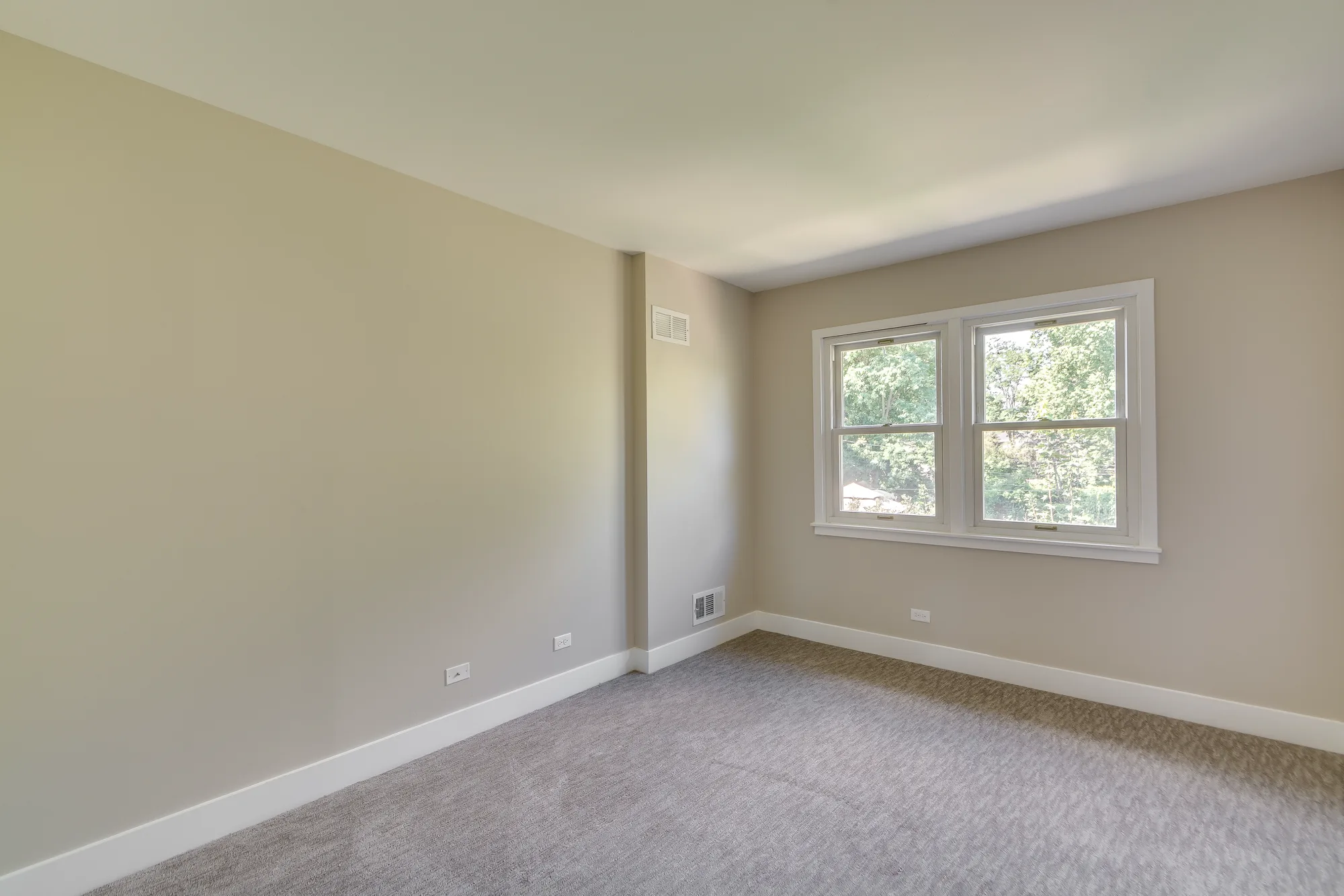 Carpeted bedroom with tree-lined views